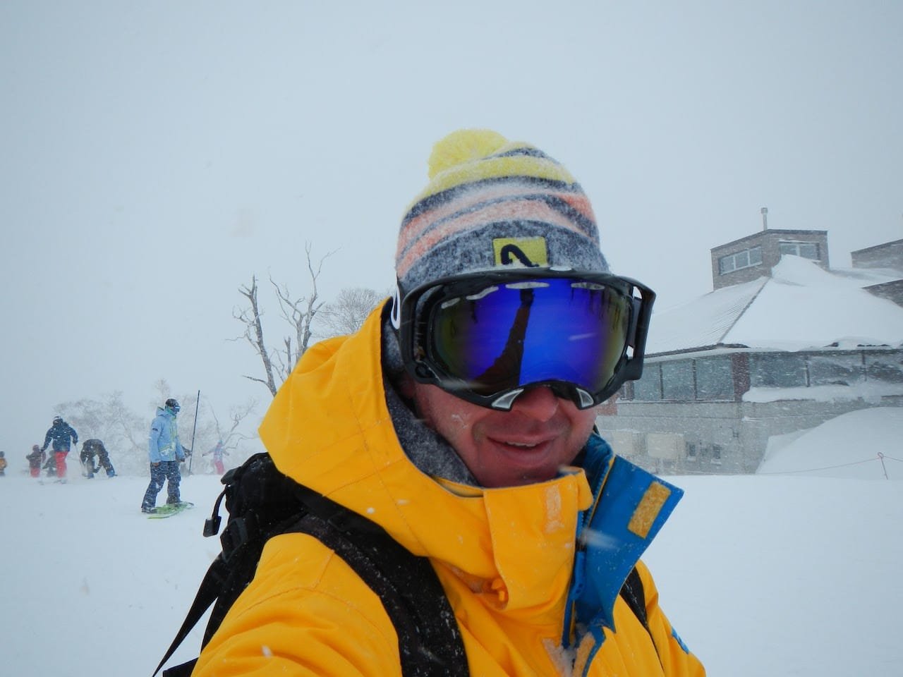 Man standing in front of a ski lodge at Niseko, Japan, during a heavy snowstorm.