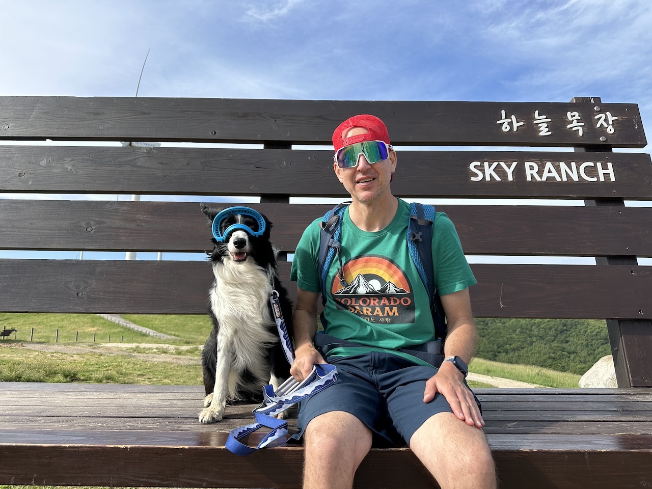 Man posing with a dog on a viewing deck at the top of the Daegwallyeong Han Neul Sky Ranch trekking trail, South Korea.