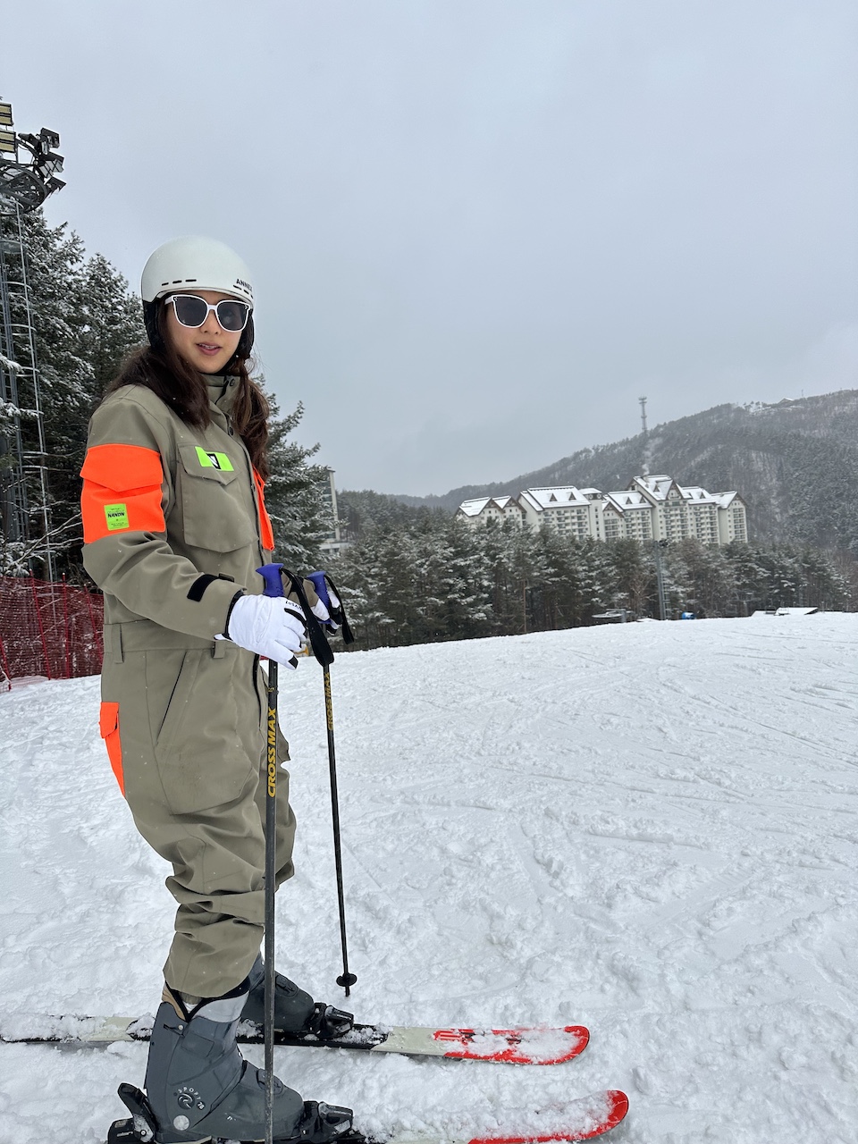 A woman in a bright pink ski suit and a white helmet with a shiny blue visor is skiing down a beginner slope at Muju Deogyusan Resort.