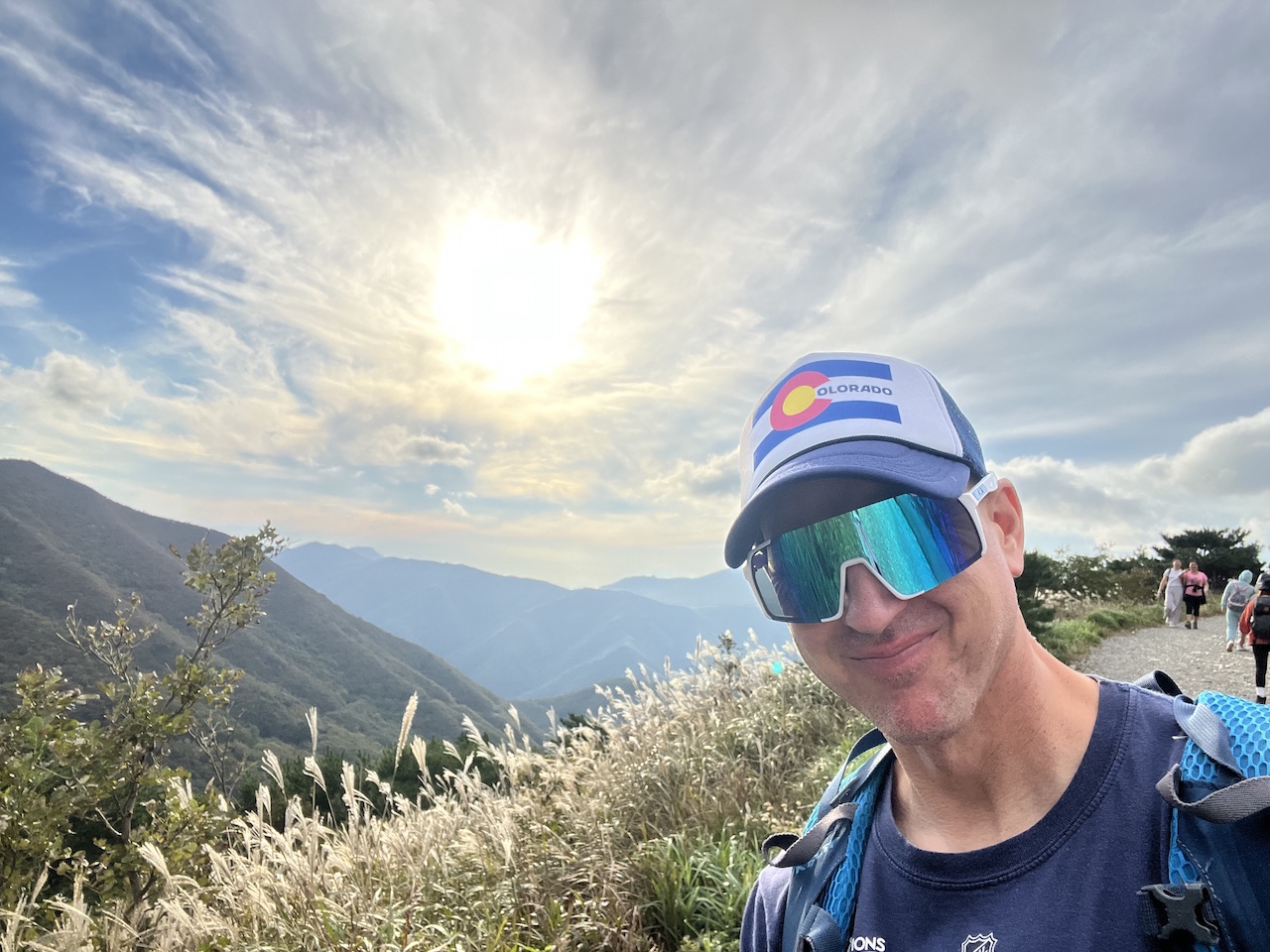 A picture of the owner of Colorado Saram hiking in South Korea wearing a Colorado flag trucker hat that is available in the online store. 