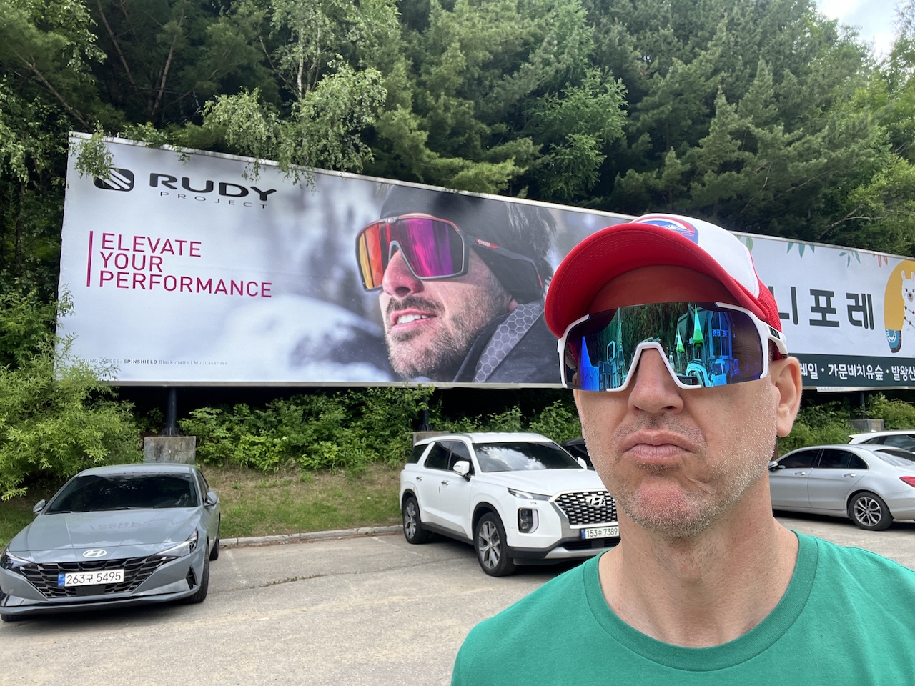 A man stands in the Gold Zone parking lot during summer, showcasing the surroundings of Yongpyong Resort.