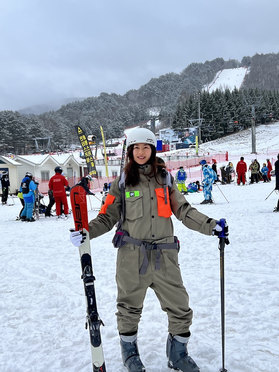 A Korean beginner skier wearing ski gear, posing happily at the base of the Silver Zone at Yongpyong Resort.