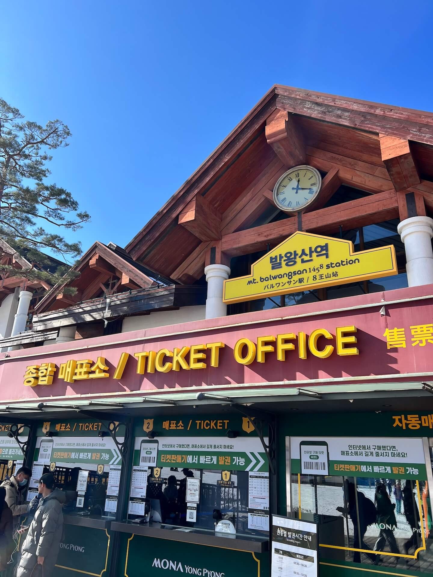 Lift ticket office at Dragon Plaza, the base of Mona Yongpyong Resort in Gangwon Province, South Korea. Featuring a bright yellow sign with "Mt. Balwangsan Station" and ticket counters.