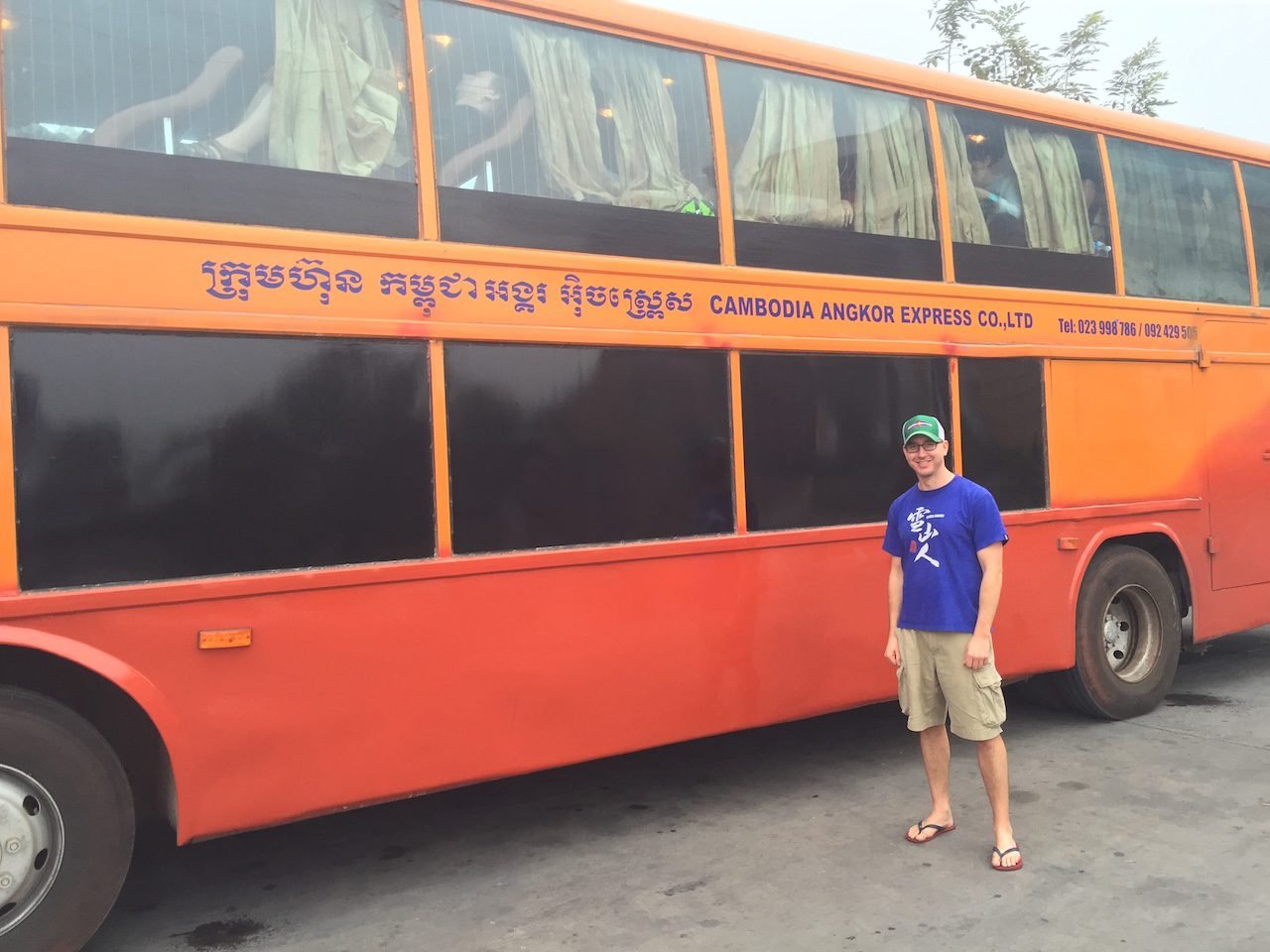 A backpacker standing in front of a sleeper bus traveling overnight from Thailand to Cambodia. 