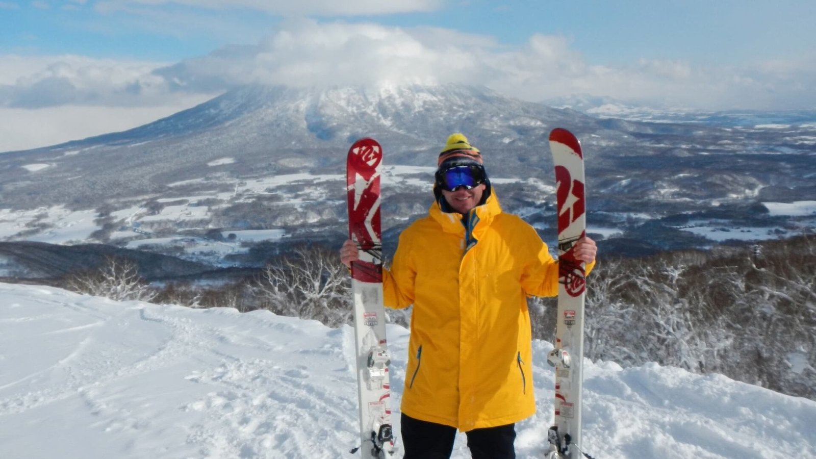 Colorado Saram at Niseko Ski Resort, Hokkaido, Japan holding powder skis, representing a Colorado lifestyle infused with adventure travel across Asia.