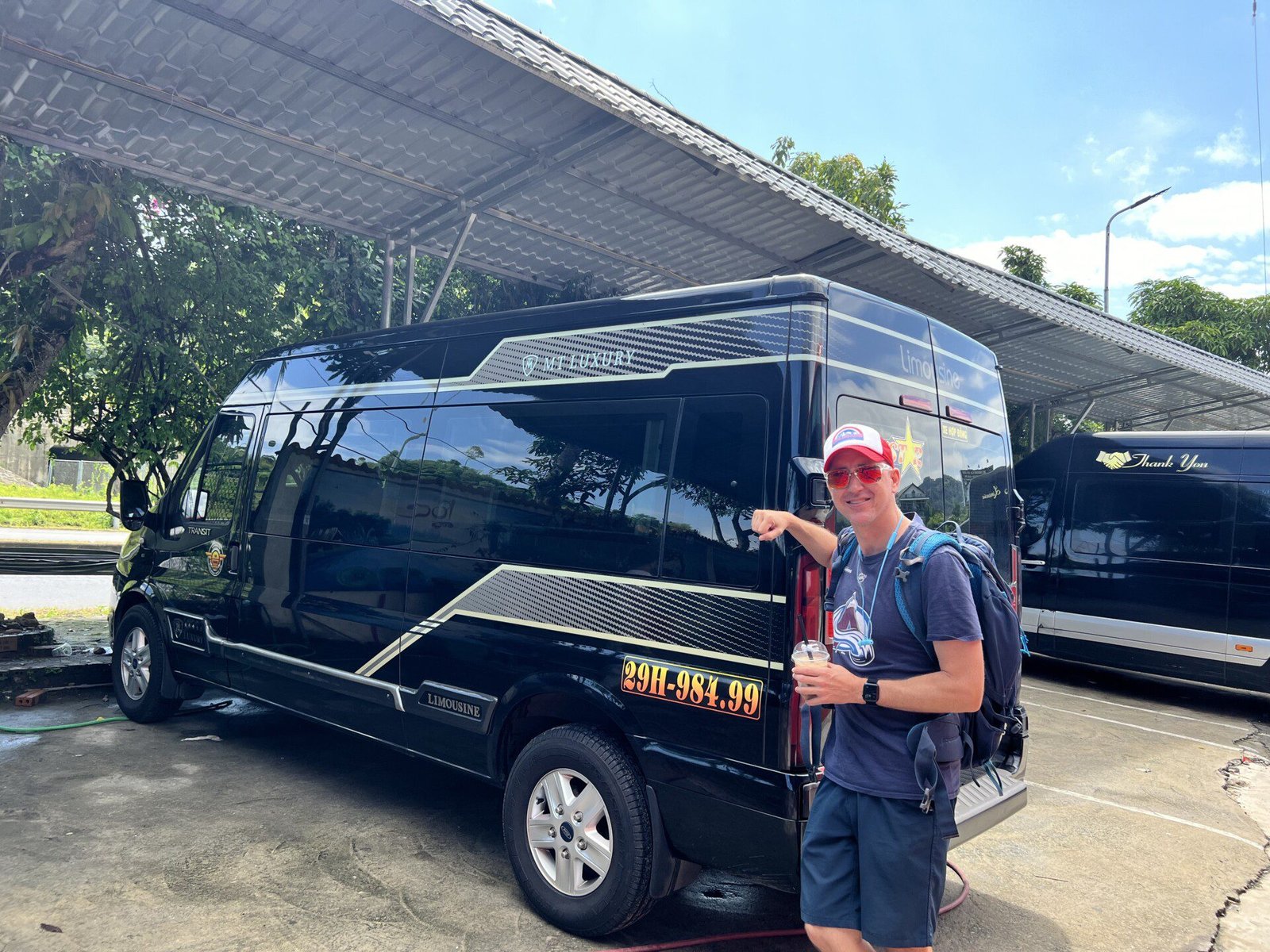 A traveler standing in front of a shiny black limousine-style mini-van used for comfortable transport between Hanoi and Sa Pa, Vietnam.