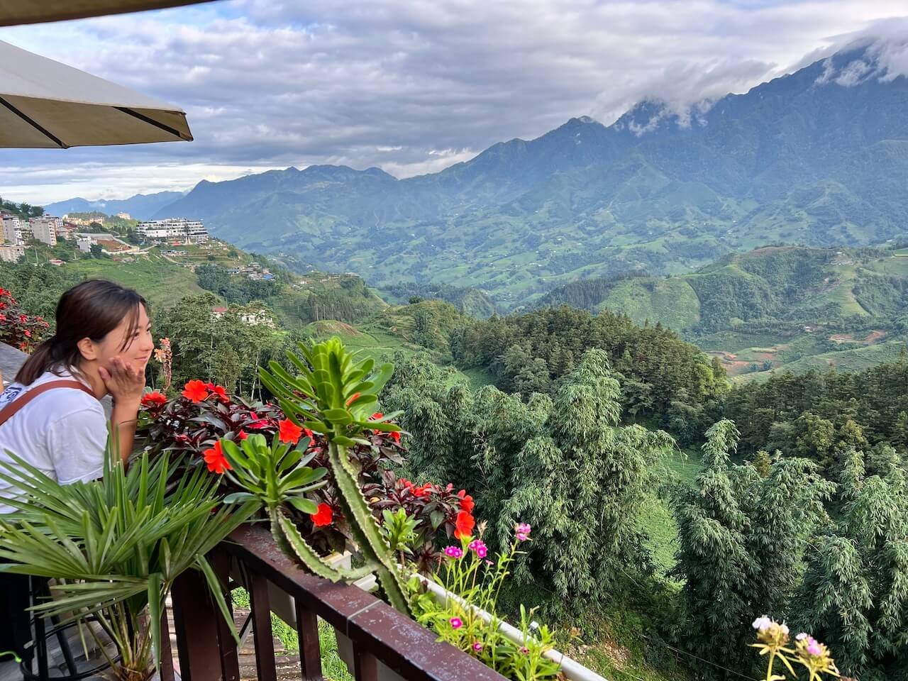 A panoramic view of Sapa’s lush green rice terraces and a winding river under cloudy skies in Vietnam.