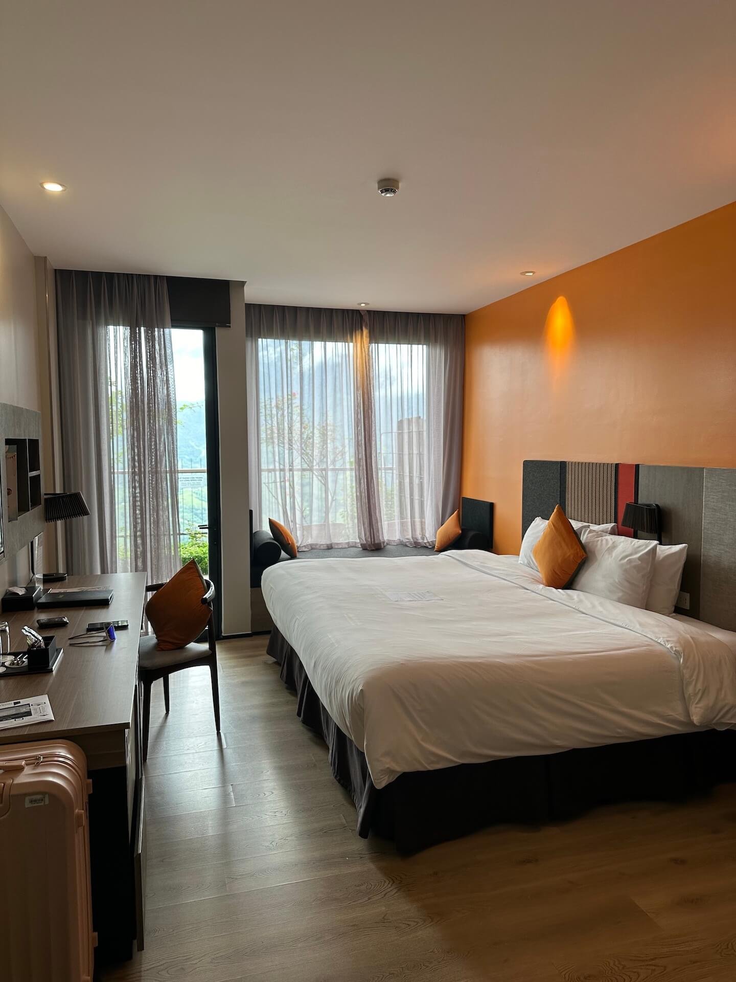 A deluxe double room at Pao’s Sapa Leisure Hotel in Sapa, Vietnam, featuring a large bed, modern decor, and floor-to-ceiling windows with a scenic valley view.