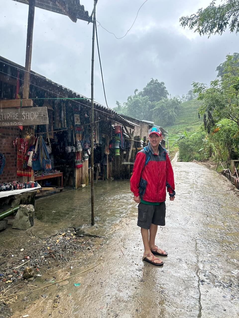 A trekker stands in the rain on the streets of Lao Chai Village during a trek in the rainy season from Sapa, Vietnam.