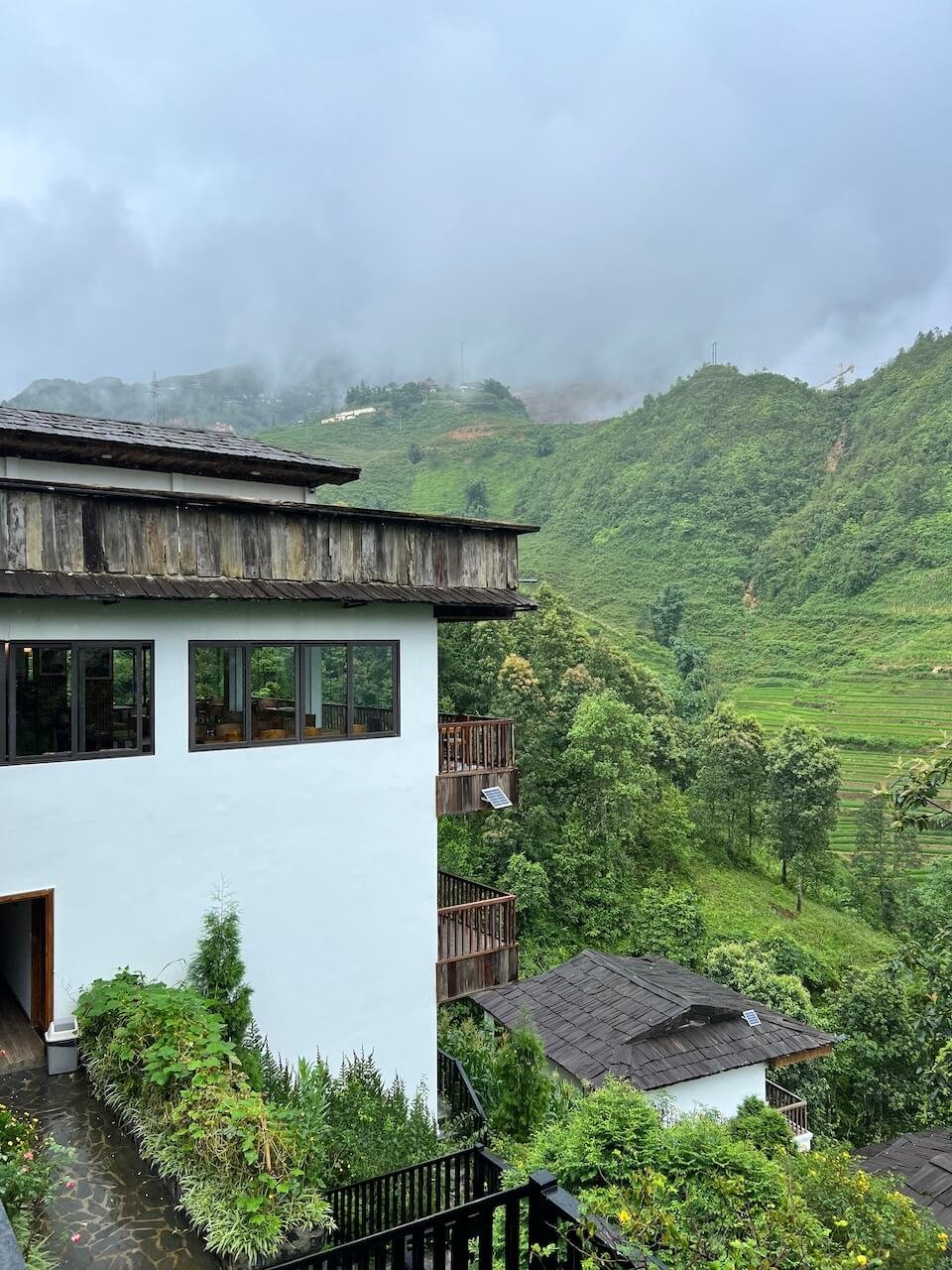 Maison de Lao Chai boutique hotel in the Lao Chai Valley, Sapa, Vietnam, with lush green rice terraces and misty mountains in the background.