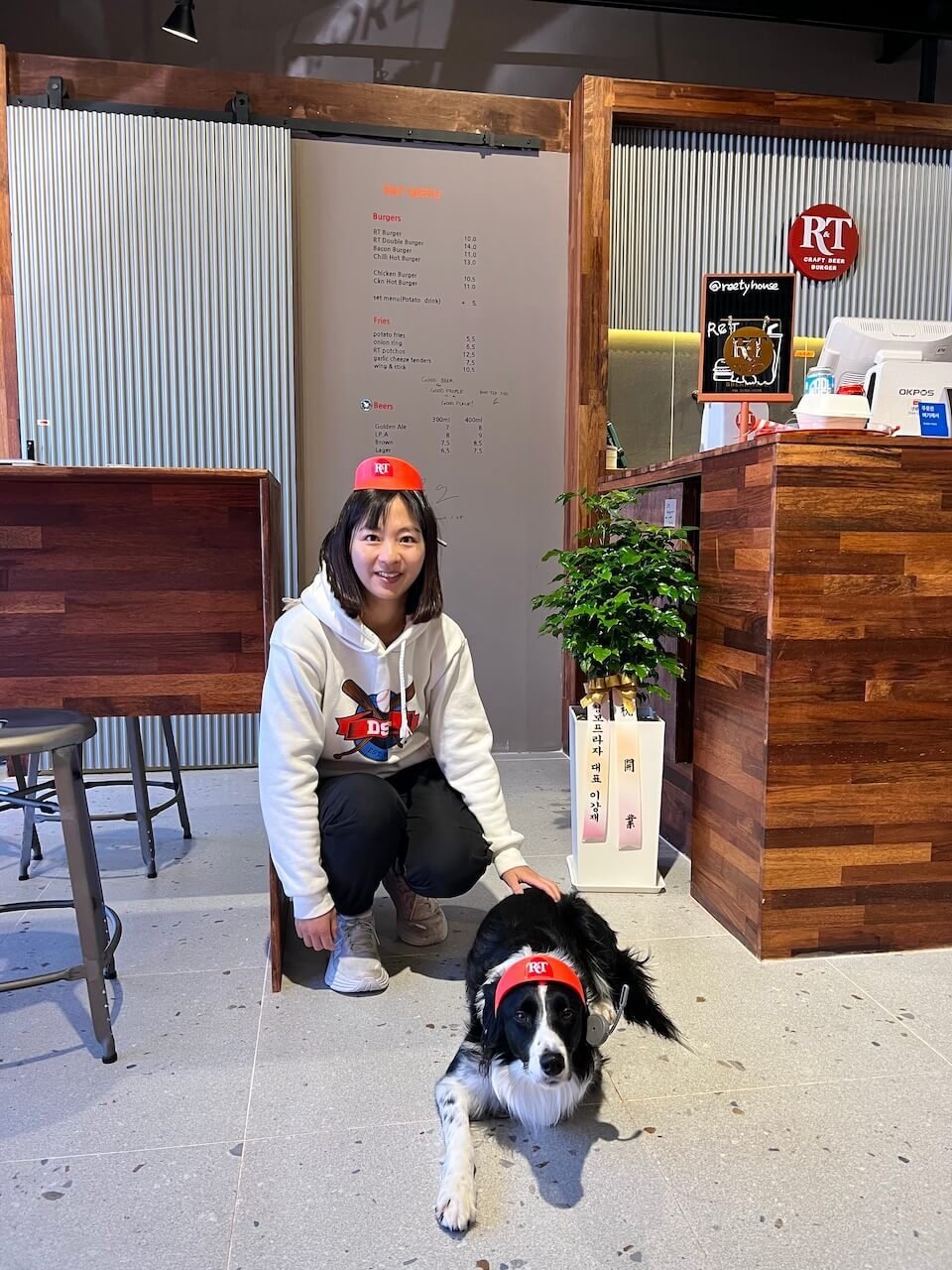 Yongpyong Resort Summer Guide (2025) 17 Woman and border collie wearing R&T hats inside dog-friendly R&T Burger House in Alpensia, South Korea