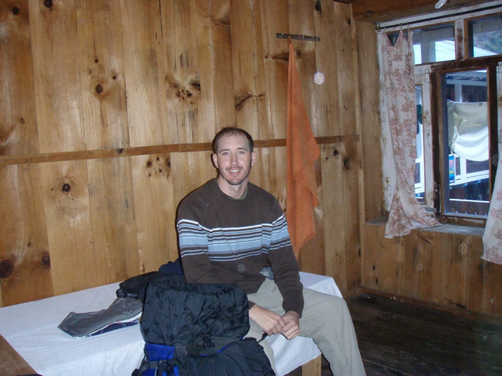Annapurna Circuit vs Everest Base Camp: How to Choose the Right Nepal Trek 10 Basic wooden teahouse room with single bed, curtain-covered window, and trekking gear in Nepal