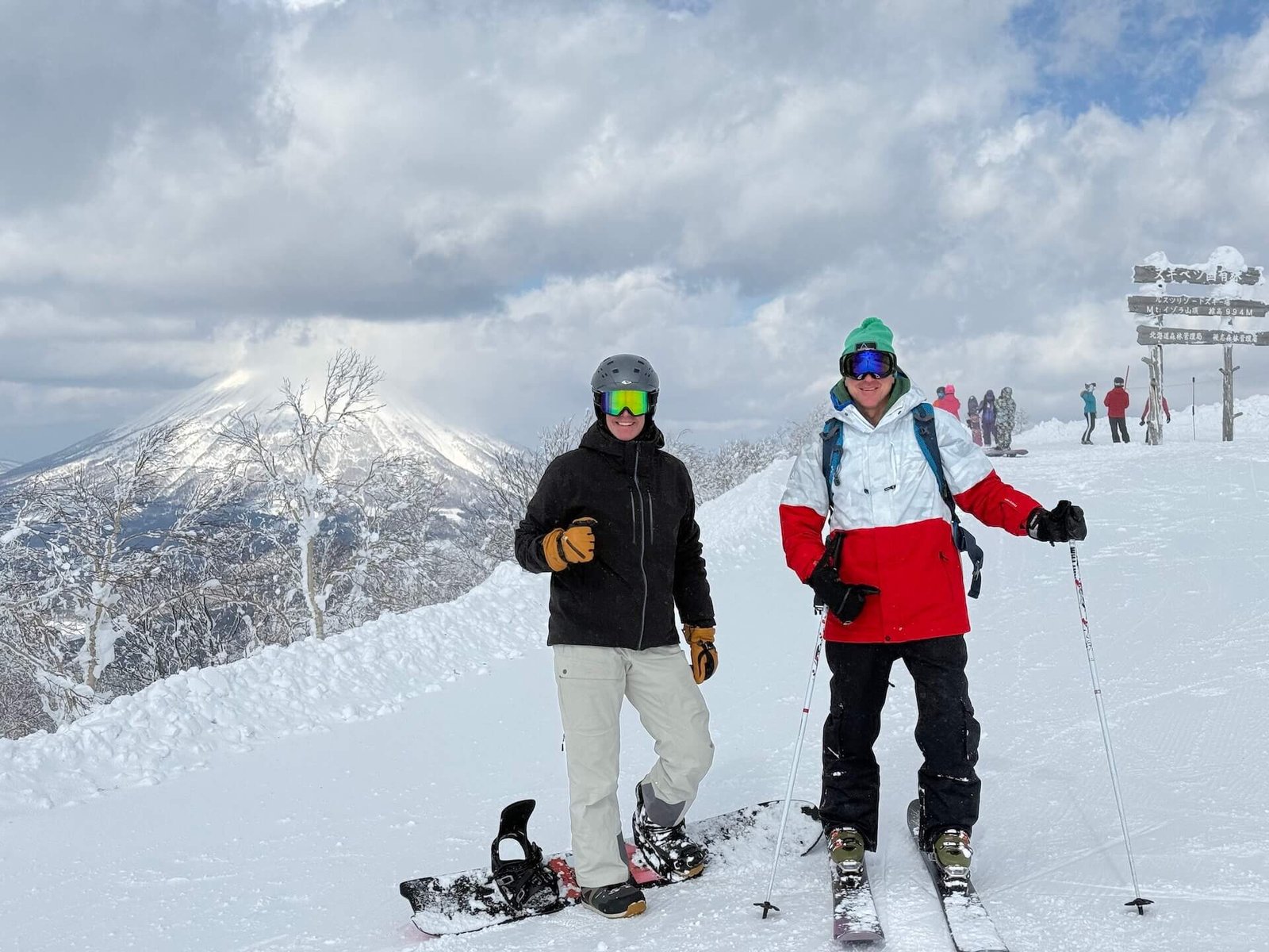 The Perfect 5–7 Day Hokkaido Ski Itinerary (2025 Guide) 4 Skier and snowboarder posing at the top of Rusutsu Resort with Mt. Yotei in the background on a clear winter day in Hokkaido